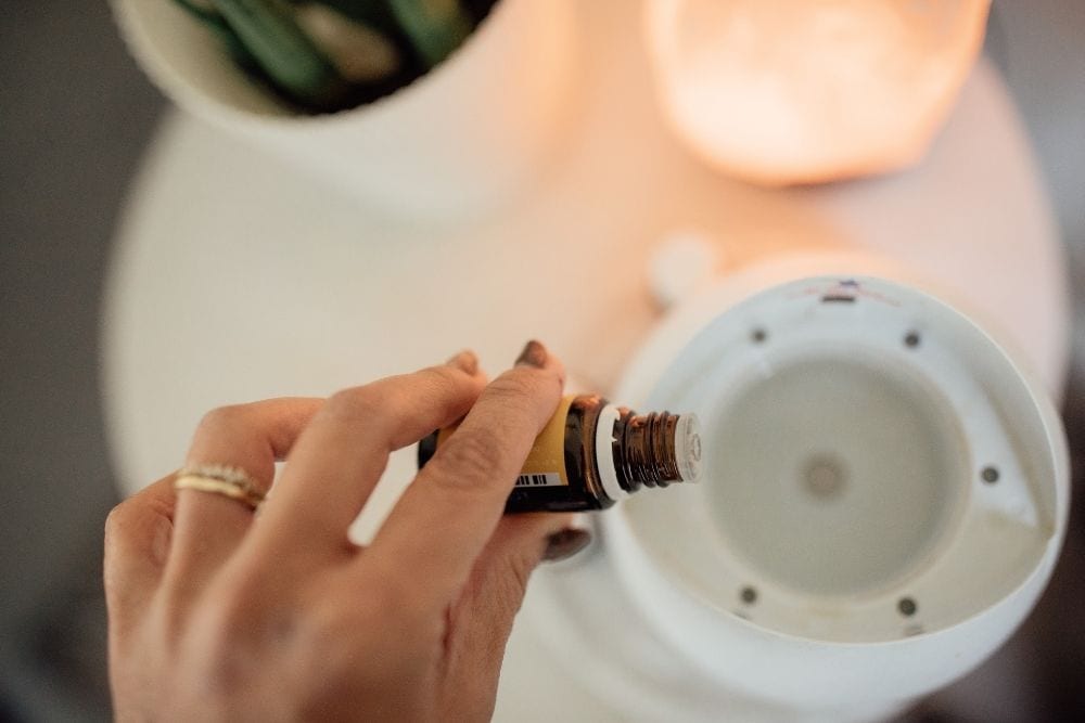 a girl pour an essential oil to a diffuser