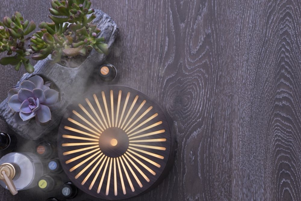 a electric diffuser, oil bottles and some flowers on woody table