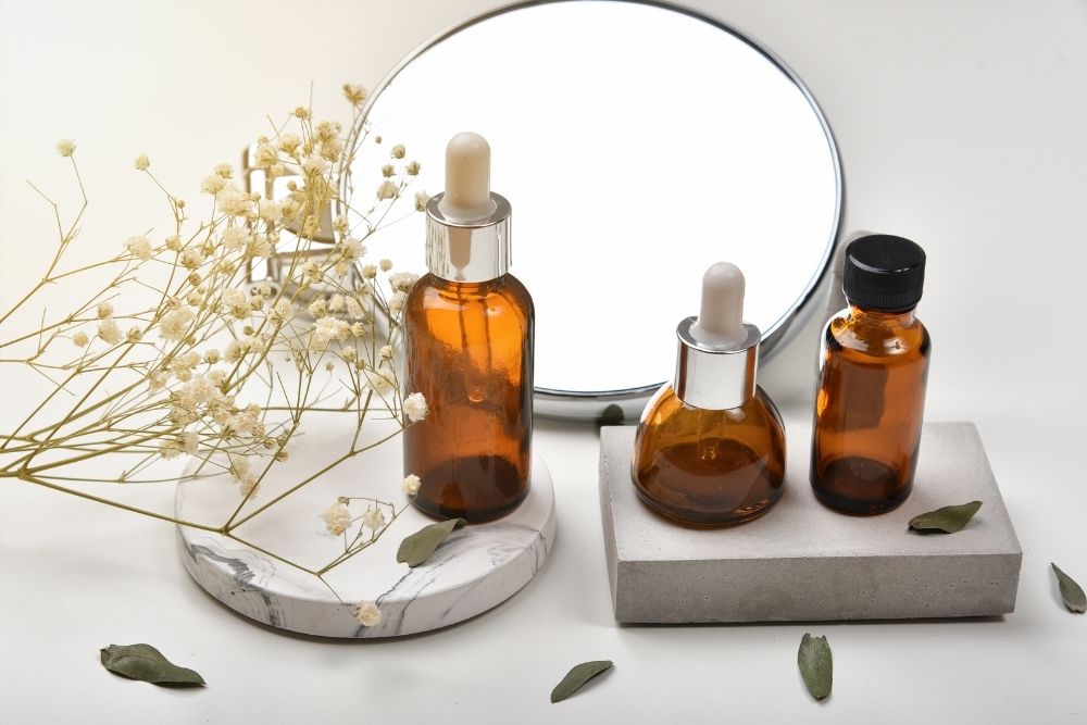 three bottles of oil with flowers and a mirror