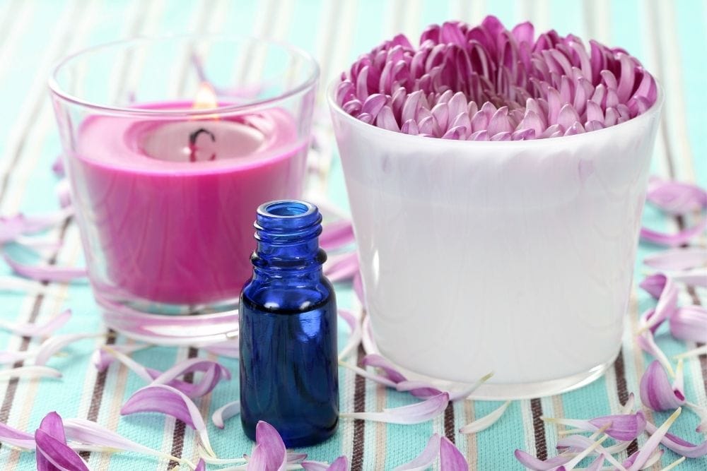 a bottle of oil, a flower in a cup and a candle glass