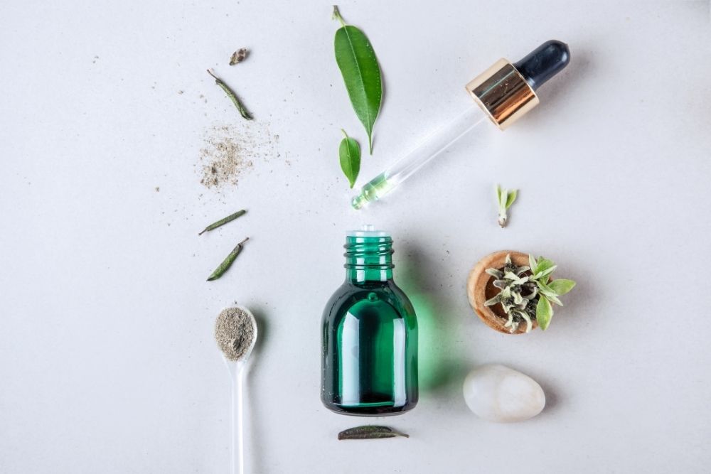 essential oil bottle with spoon, rock, leaf